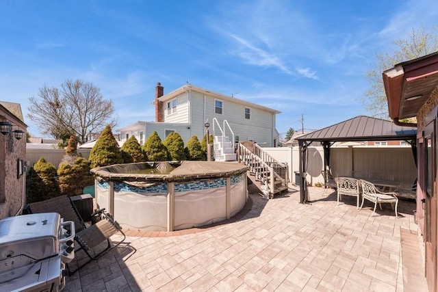 view of patio with stairway, a fenced backyard, a fenced in pool, and a gazebo