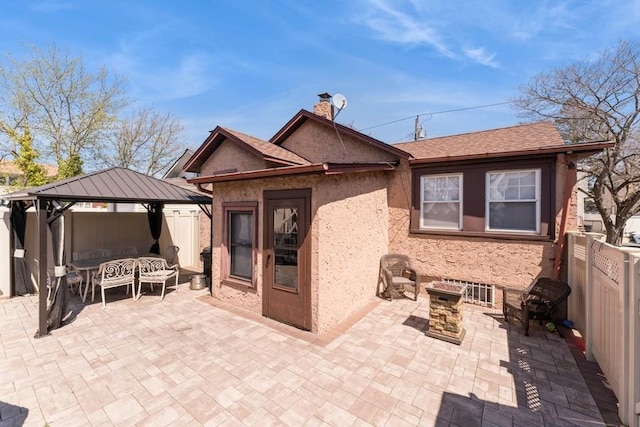 rear view of house featuring a gazebo, a patio area, a chimney, and fence