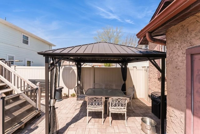 view of patio / terrace with a gazebo, outdoor dining area, stairs, and fence