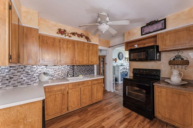 kitchen featuring a ceiling fan, tasteful backsplash, a sink, black appliances, and brown cabinets