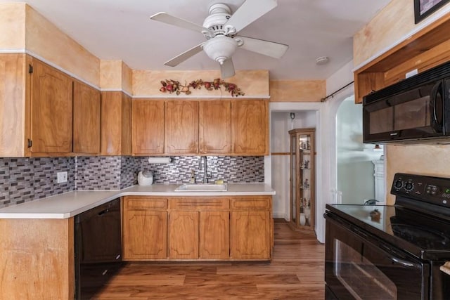 kitchen featuring a sink, light wood-style floors, a ceiling fan, light countertops, and black appliances