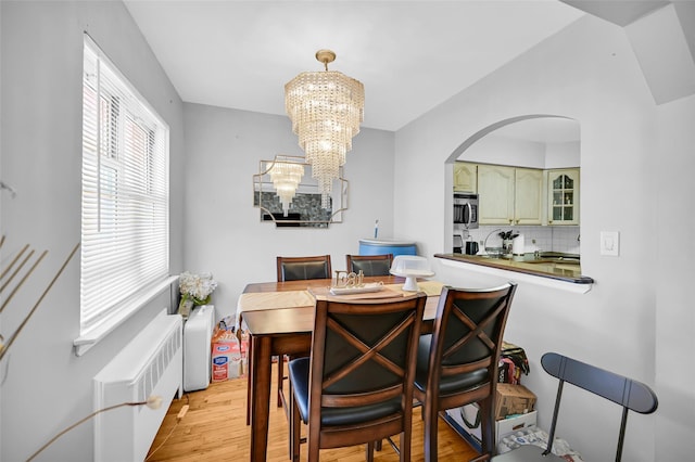 4415 Mundy Ln, Bronx, NY 10466 - dining area featuring radiator heating unit, arched walkways, light wood-style floors, and a chandelier