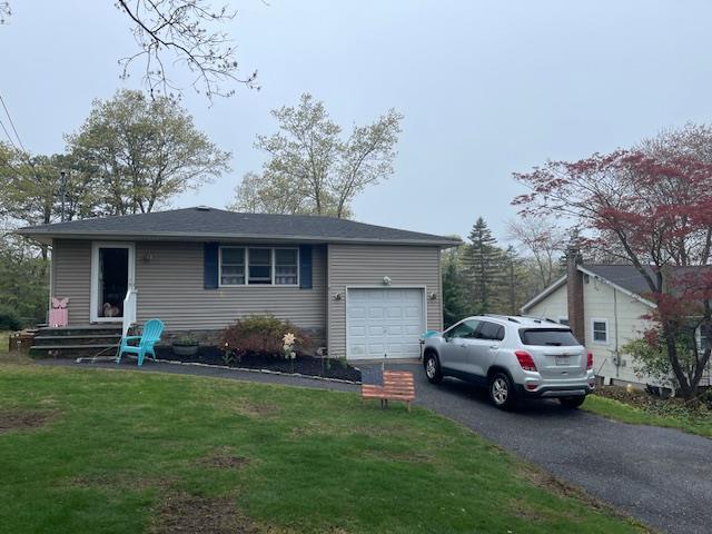 view of front of home with an attached garage, asphalt driveway, and a front yard
