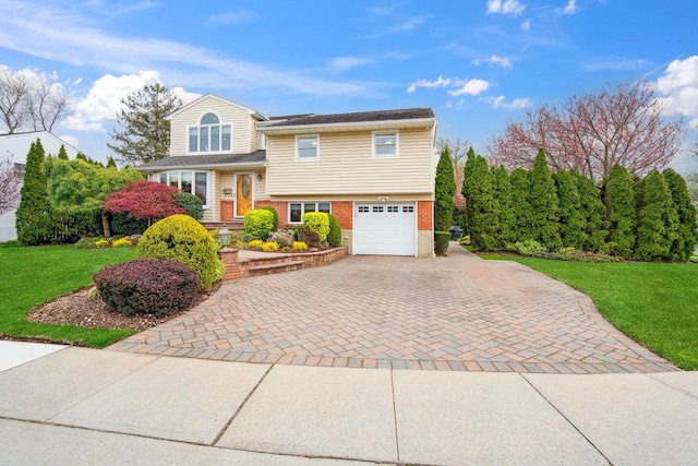 split level home with brick siding, decorative driveway, a front yard, and a garage