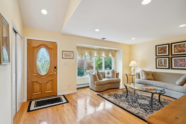 living area with a baseboard heating unit, baseboards, light wood-style floors, and recessed lighting