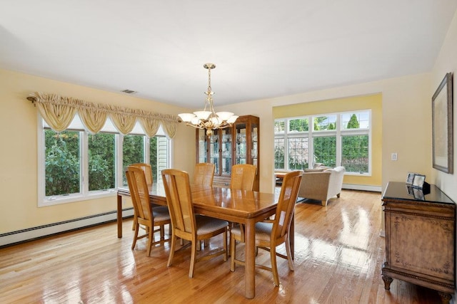 dining space featuring an inviting chandelier, visible vents, a baseboard heating unit, light wood-style floors, and baseboard heating