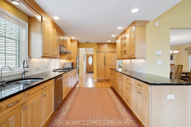 kitchen featuring recessed lighting, stainless steel appliances, dark stone countertops, a sink, and light wood-type flooring