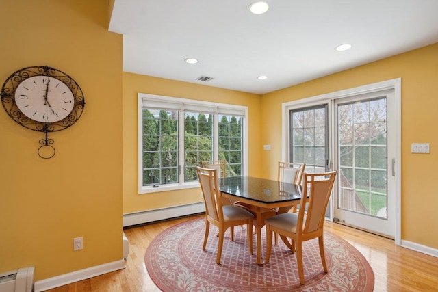dining space featuring a baseboard radiator, light wood-style floors, visible vents, and baseboards