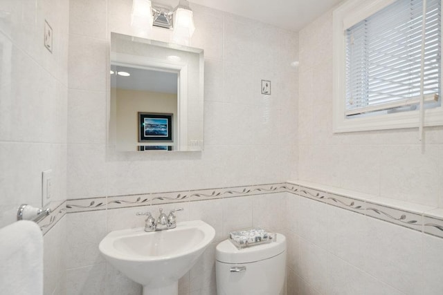 bathroom featuring tile walls, a sink, and toilet
