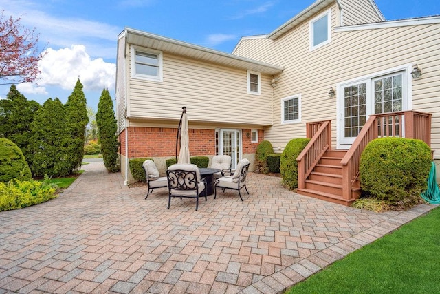 rear view of house featuring brick siding, a deck, a patio, and outdoor dining space