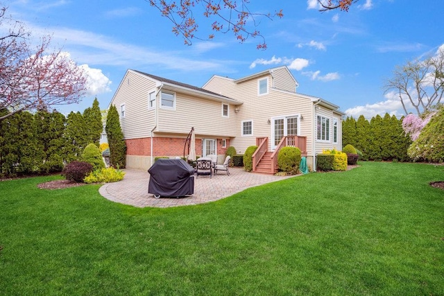 rear view of property featuring brick siding, a yard, and a patio