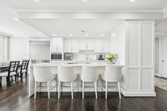 kitchen with light countertops, stainless steel oven, white cabinets, and dark wood-style flooring
