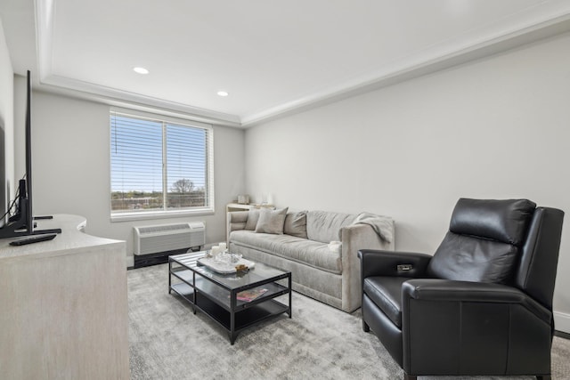 living area with a tray ceiling, a wall unit AC, baseboards, recessed lighting, and light colored carpet