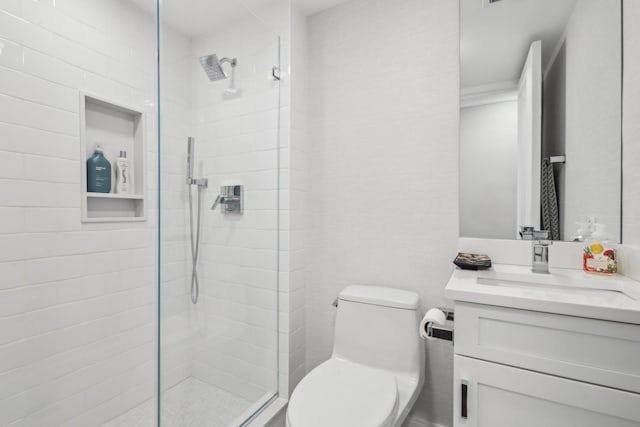 bathroom with a tile shower, toilet, and vanity