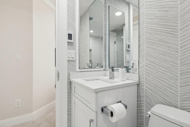 bathroom with baseboards, tile walls, toilet, and vanity