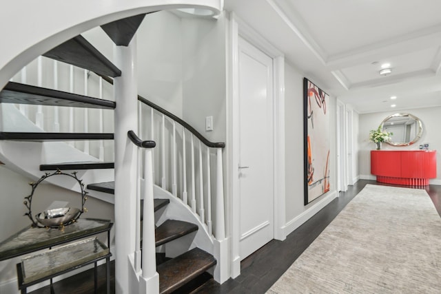 stairway featuring recessed lighting, baseboards, wood finished floors, and a raised ceiling