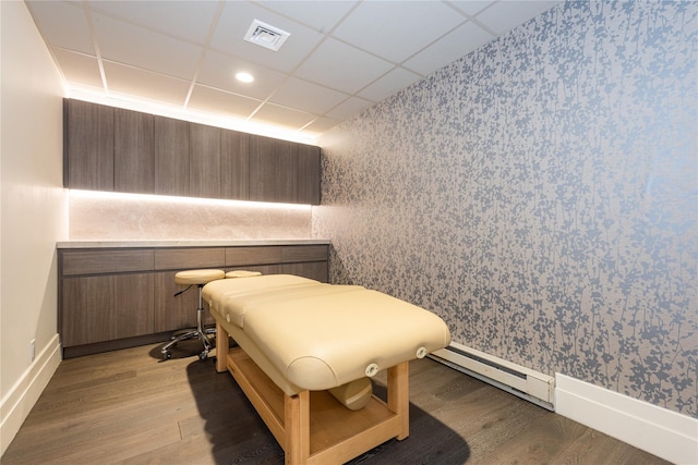 bedroom featuring light wood-type flooring, visible vents, baseboards, wallpapered walls, and baseboard heating
