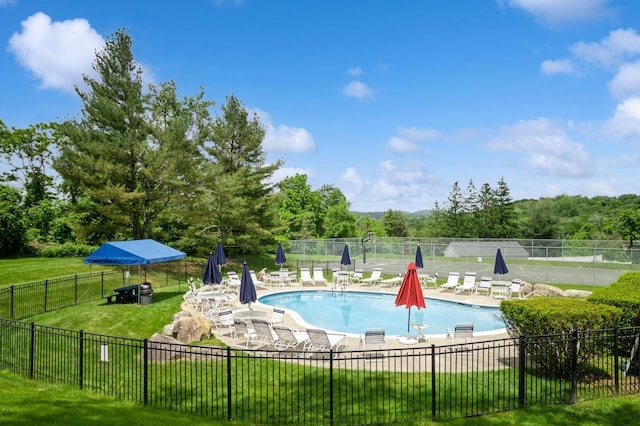 pool featuring fence, a patio area, and a lawn
