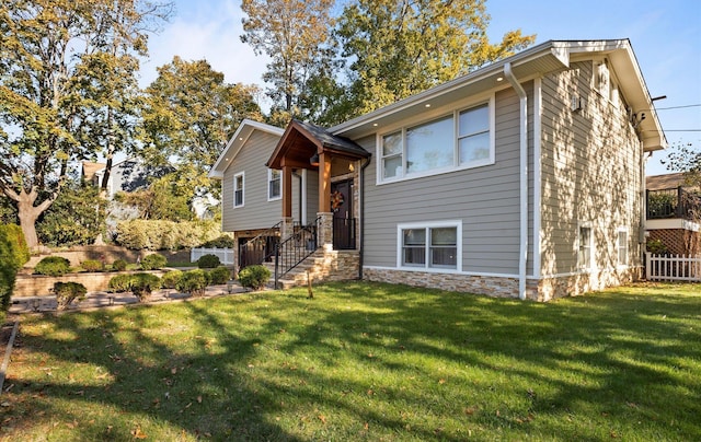 split foyer home featuring fence, a front lawn, and stone siding