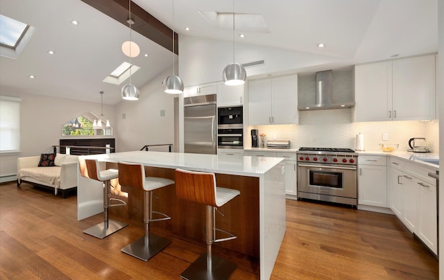 kitchen with a center island, lofted ceiling with skylight, visible vents, high quality appliances, and wall chimney range hood