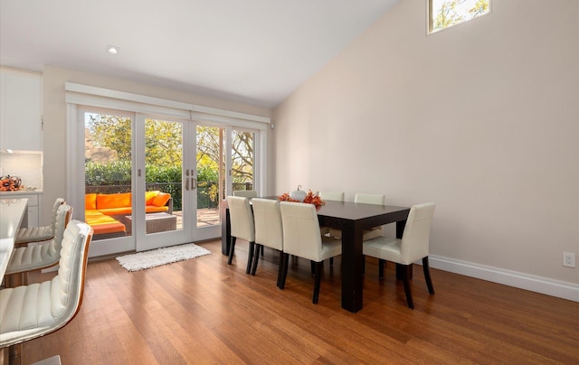 dining space with lofted ceiling, french doors, a healthy amount of sunlight, and wood finished floors