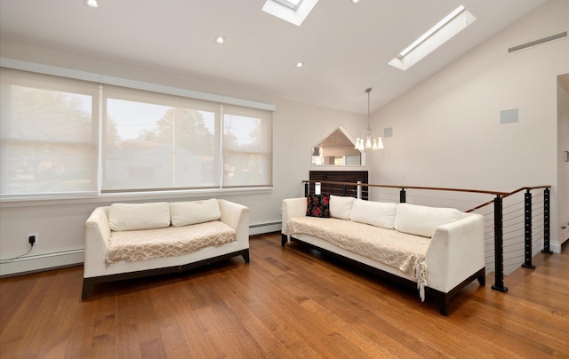living area featuring wood finished floors, a skylight, a notable chandelier, visible vents, and a baseboard heating unit