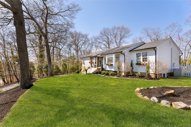 view of front facade featuring central AC unit, roof with shingles, fence, and a front yard