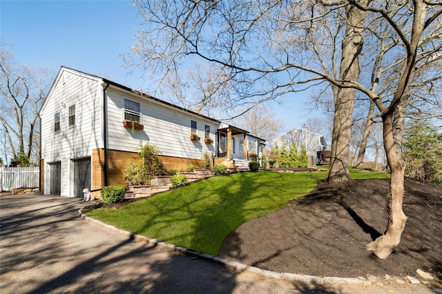 exterior space with an attached garage, aphalt driveway, fence, and a front lawn