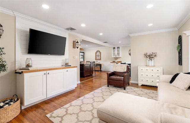 living area featuring recessed lighting, crown molding, and light wood-type flooring