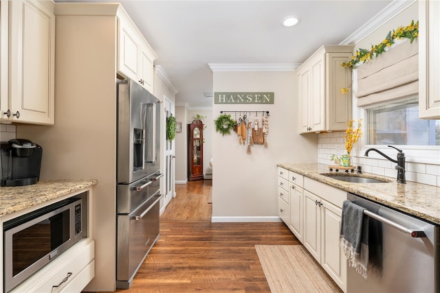 kitchen featuring recessed lighting, stainless steel appliances, ornamental molding, a sink, and dark wood-style flooring