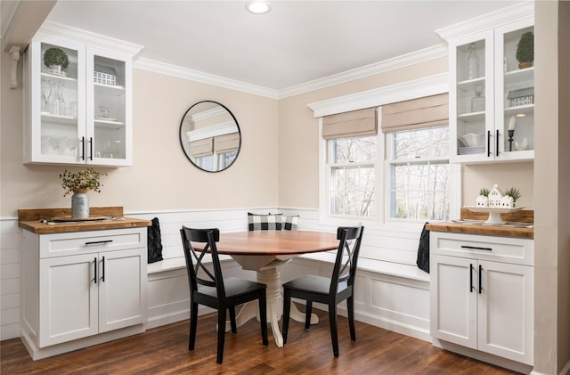 dining space featuring a wainscoted wall, dark wood-style floors, crown molding, breakfast area, and a decorative wall