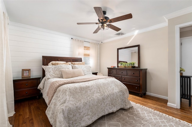bedroom featuring baseboards, ornamental molding, wood finished floors, and visible vents