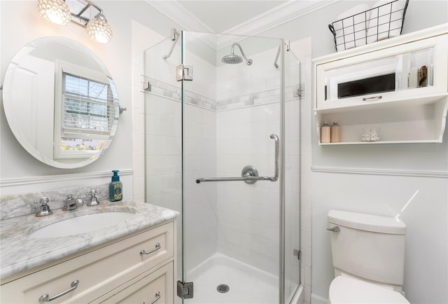 bathroom featuring a shower stall, toilet, crown molding, and vanity