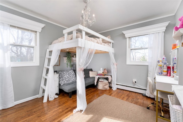 bedroom with a chandelier, a baseboard radiator, wood finished floors, and multiple windows