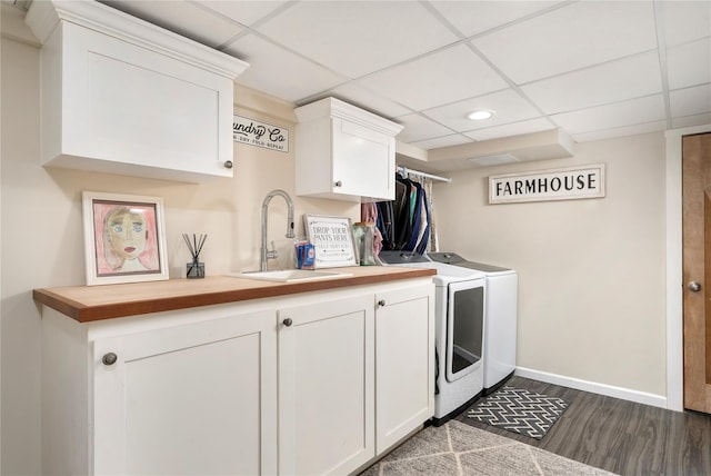 laundry room featuring washing machine and clothes dryer, a sink, dark wood-style flooring, baseboards, and cabinet space