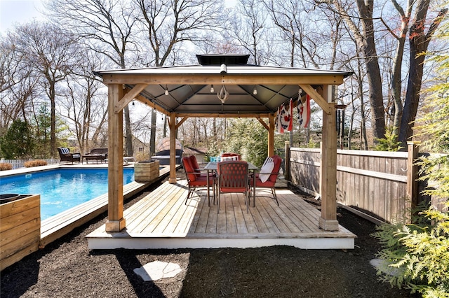 deck with outdoor dining area, a gazebo, fence, and a fenced in pool