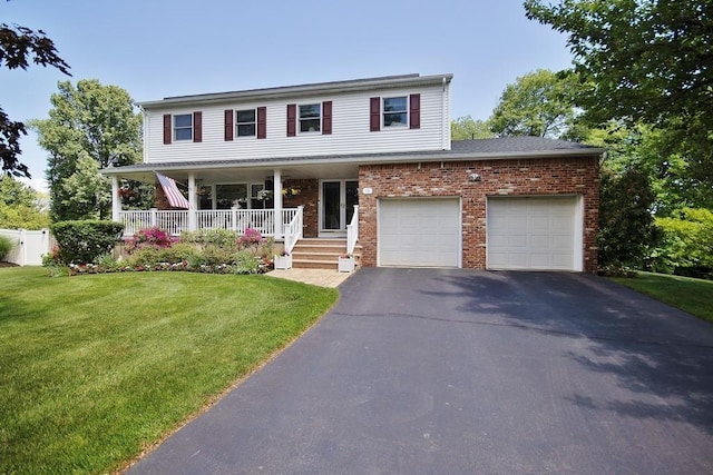 view of front of home with driveway, brick siding, a porch, and a front lawn