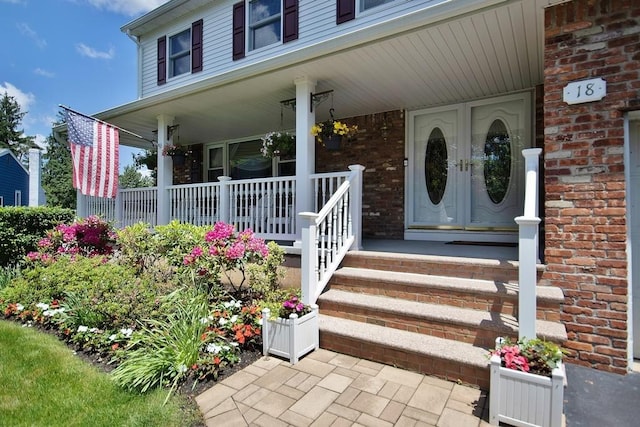 property entrance with covered porch and brick siding