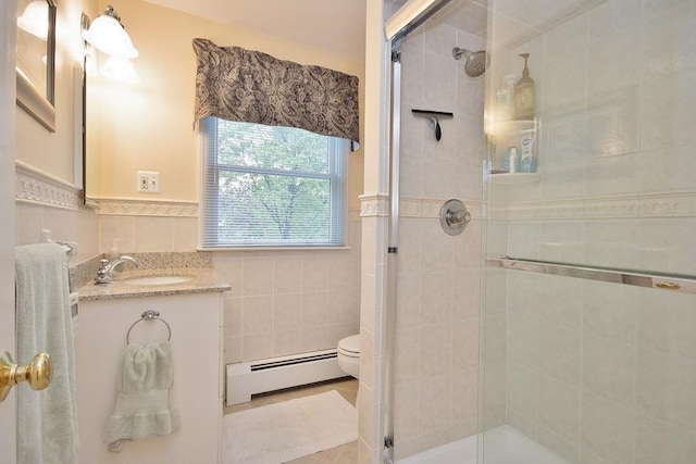 bathroom featuring tile walls, wainscoting, a stall shower, vanity, and a baseboard heating unit