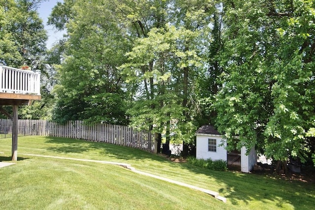 view of yard featuring an outbuilding, a deck, a storage unit, and fence