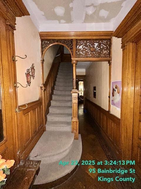stairs featuring wooden walls and wainscoting