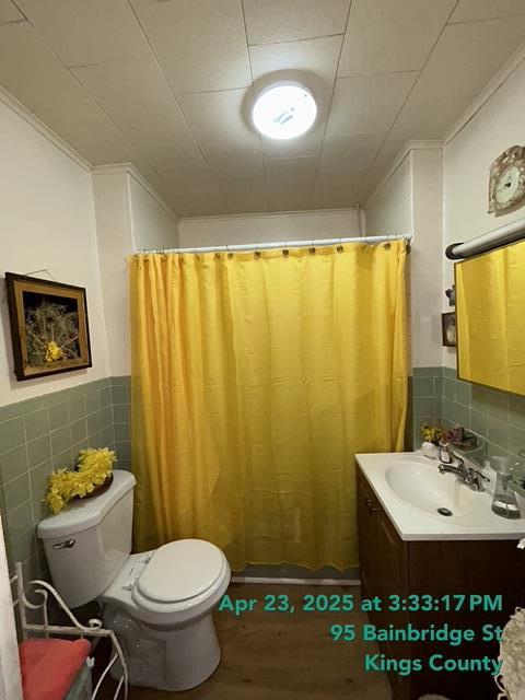 bathroom with vanity, toilet, a shower with shower curtain, tile walls, and wood finished floors