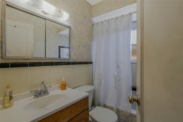 bathroom featuring vanity, toilet, tile walls, wallpapered walls, and shower / bath combo