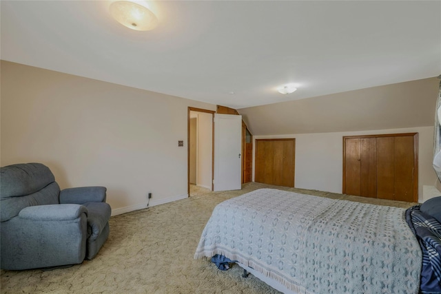 bedroom with baseboards, vaulted ceiling, and light carpet