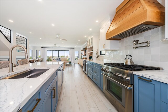 923 Oceanfront, Long Beach, NY 11561 - kitchen with high end stainless steel range oven, custom range hood, blue cabinets, a sink, and white cabinets