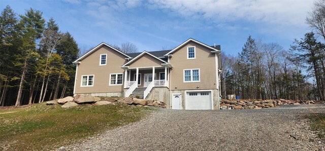 traditional-style home featuring gravel driveway, a garage, stairway, and covered porch