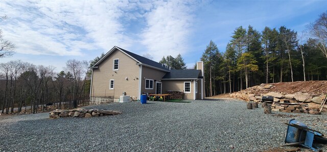 view of home's exterior with a chimney and central AC unit
