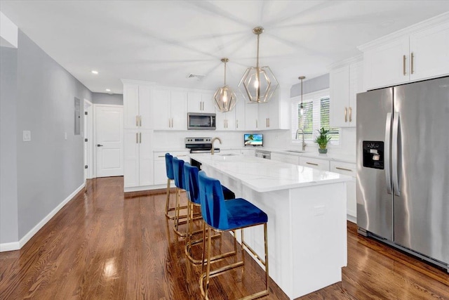 kitchen with a sink, stainless steel appliances, recessed lighting, white cabinetry, and a center island with sink