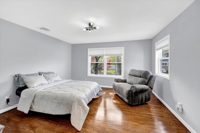 bedroom with baseboards, visible vents, multiple windows, and wood finished floors