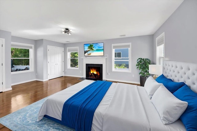 bedroom with baseboards, wood finished floors, and multiple windows